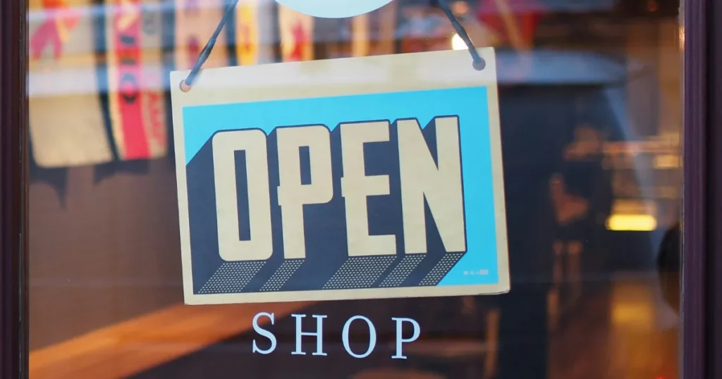 A close-up of an 'Open' sign hanging on the glass door of a shop, reflecting a cozy and inviting interior.